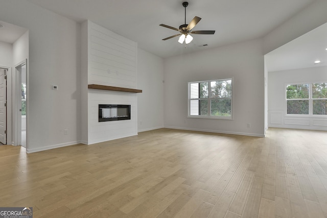 unfurnished living room featuring a fireplace, ceiling fan, and light wood-type flooring