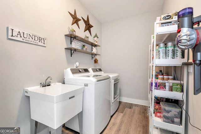 laundry area featuring separate washer and dryer, sink, and light hardwood / wood-style floors