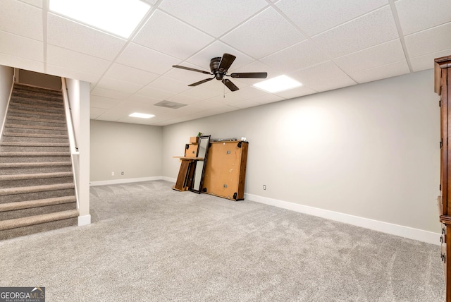 basement with carpet flooring, a paneled ceiling, and ceiling fan