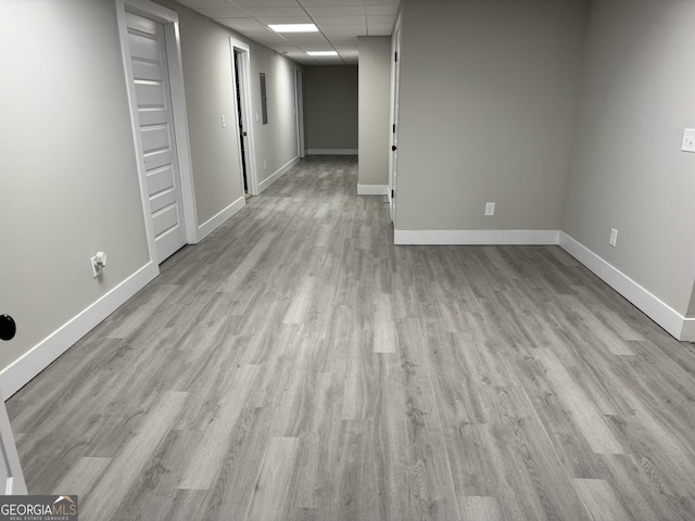 empty room with a paneled ceiling and light hardwood / wood-style flooring