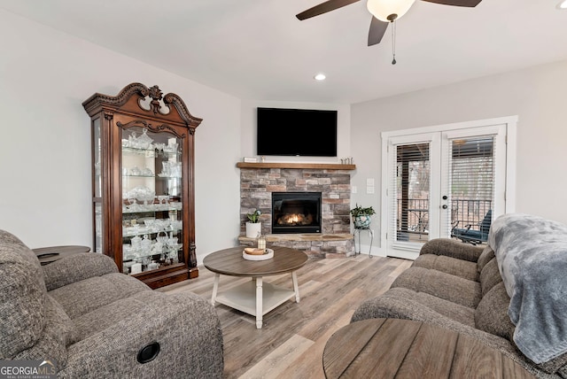 living room with ceiling fan, a fireplace, light hardwood / wood-style floors, and french doors