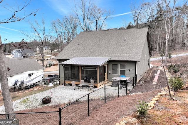 back of house with a fire pit and a sunroom