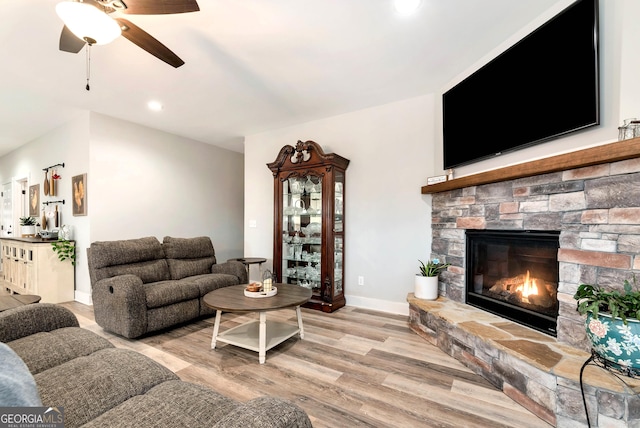 living room with a fireplace, light hardwood / wood-style floors, and ceiling fan