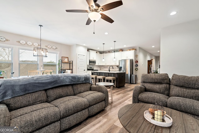 living room featuring ceiling fan, sink, and light hardwood / wood-style floors