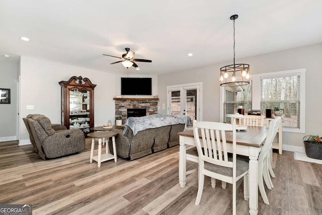 dining area featuring ceiling fan, a fireplace, light wood-type flooring, and french doors