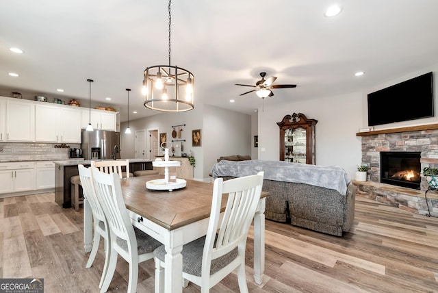 dining space featuring a fireplace, light hardwood / wood-style floors, and ceiling fan