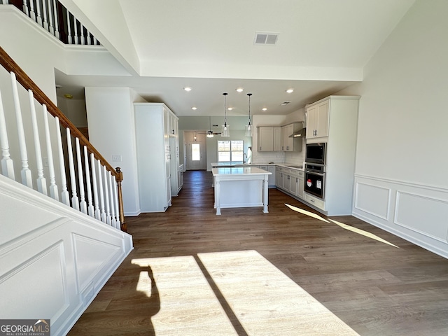 kitchen featuring pendant lighting, white cabinetry, backsplash, a kitchen island, and stainless steel oven