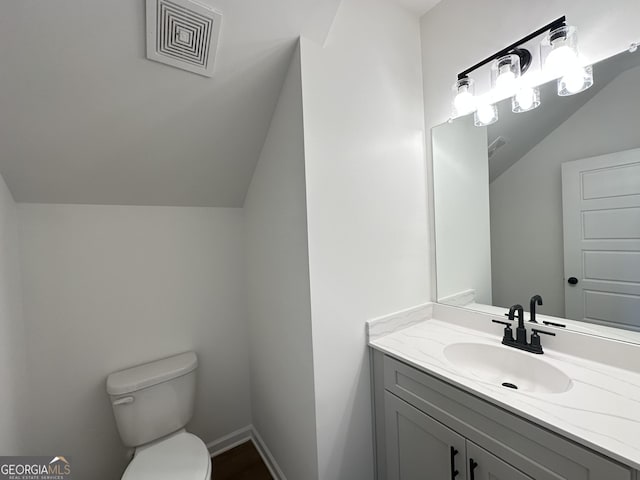 bathroom featuring vanity, vaulted ceiling, and toilet