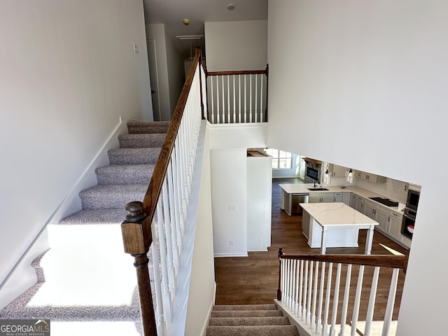 staircase featuring hardwood / wood-style flooring and a high ceiling