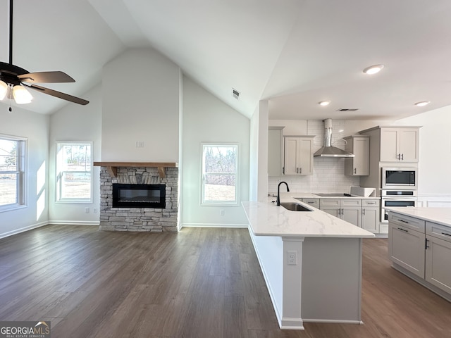 kitchen featuring sink, vaulted ceiling, oven, decorative backsplash, and wall chimney range hood