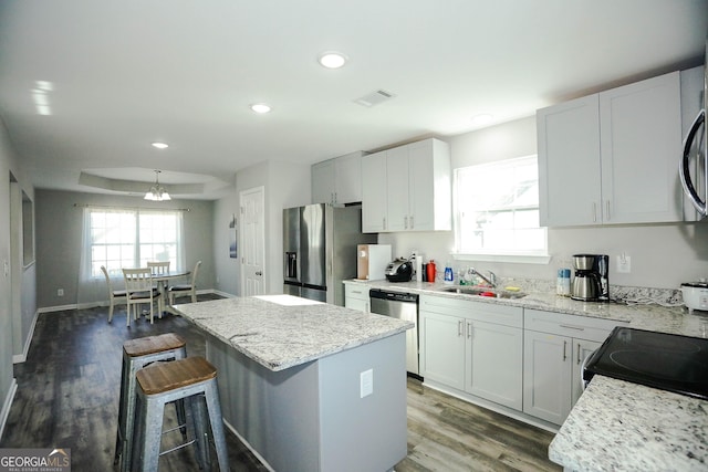 kitchen featuring white cabinetry, light stone counters, a center island, and appliances with stainless steel finishes