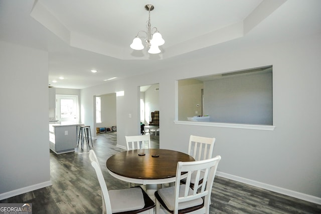 dining room with a raised ceiling, a notable chandelier, and dark hardwood / wood-style flooring