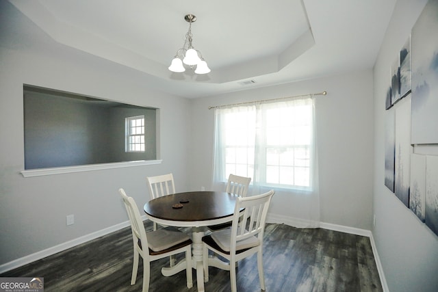 dining space with dark hardwood / wood-style flooring, a notable chandelier, and a raised ceiling