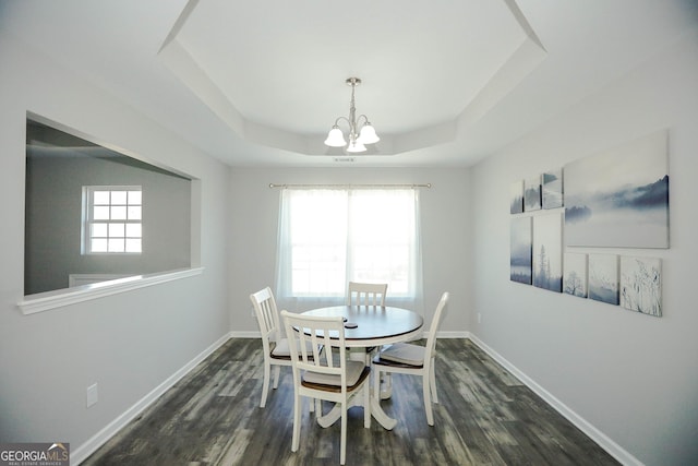 dining space featuring dark wood-type flooring, plenty of natural light, a tray ceiling, and a notable chandelier