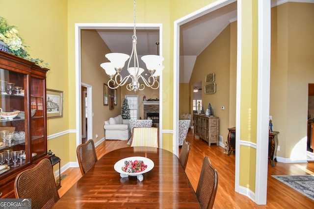 dining space with hardwood / wood-style floors, a notable chandelier, and a fireplace