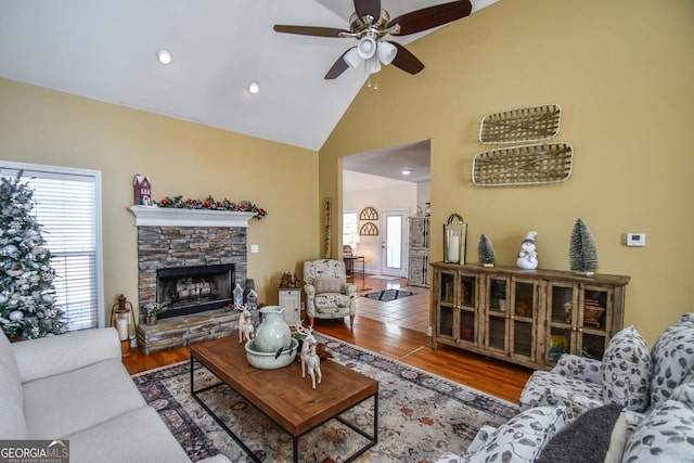 living room featuring hardwood / wood-style flooring, ceiling fan, high vaulted ceiling, and a fireplace