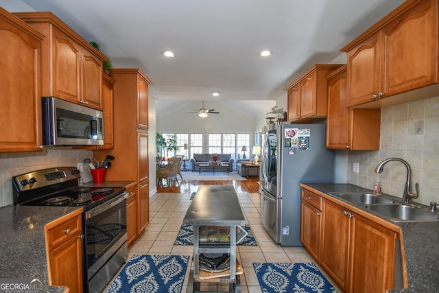 kitchen featuring light tile patterned flooring, appliances with stainless steel finishes, lofted ceiling, sink, and backsplash