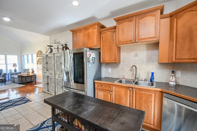 kitchen with lofted ceiling, sink, backsplash, stainless steel appliances, and light tile patterned flooring