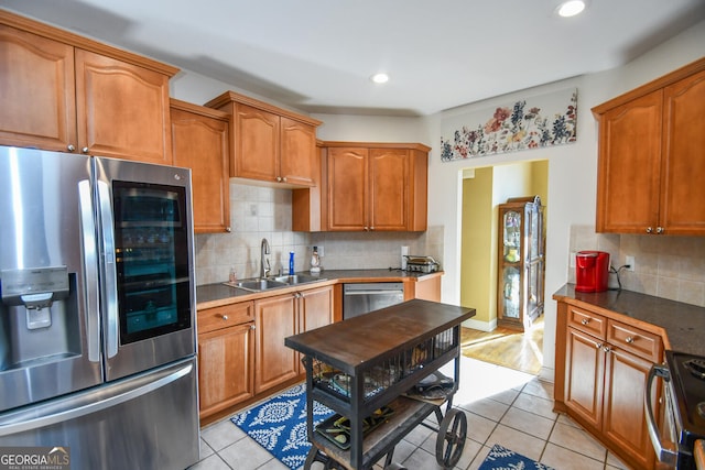 kitchen featuring appliances with stainless steel finishes, sink, light tile patterned floors, and decorative backsplash