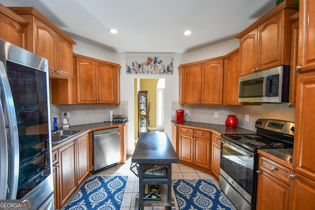 kitchen with light tile patterned flooring, stainless steel appliances, sink, and backsplash