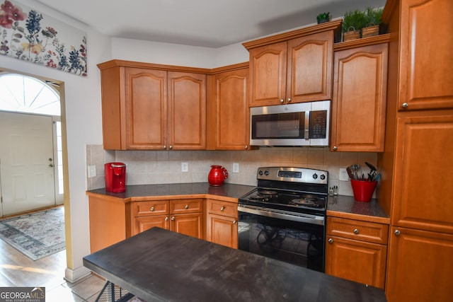 kitchen with light tile patterned flooring, electric range, and decorative backsplash