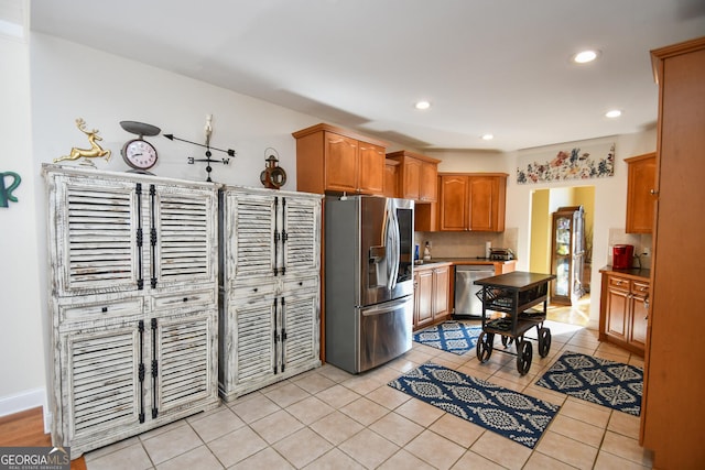 kitchen featuring appliances with stainless steel finishes, light tile patterned floors, and decorative backsplash