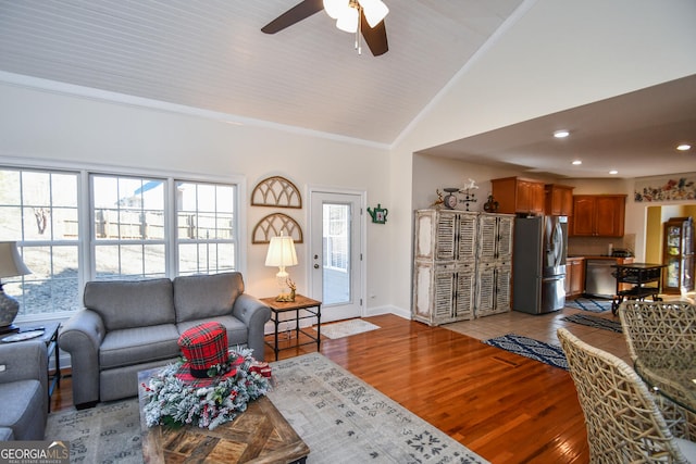 living room featuring crown molding, ceiling fan, lofted ceiling, and light wood-type flooring