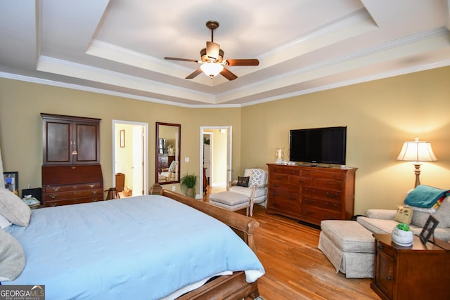 bedroom with crown molding, ceiling fan, a raised ceiling, and light hardwood / wood-style floors