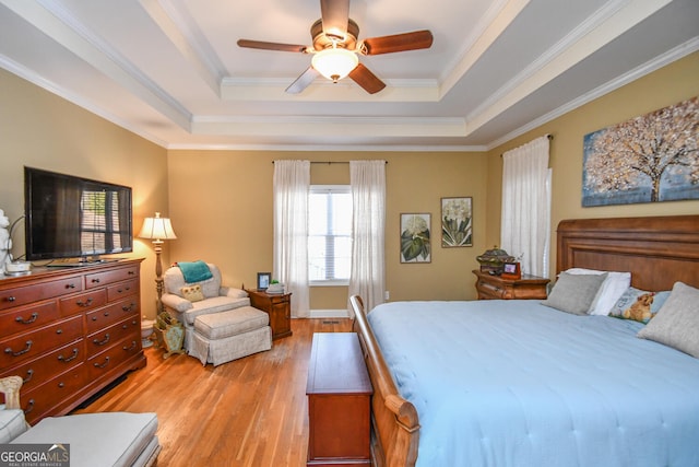 bedroom with a raised ceiling, ornamental molding, ceiling fan, and light hardwood / wood-style flooring