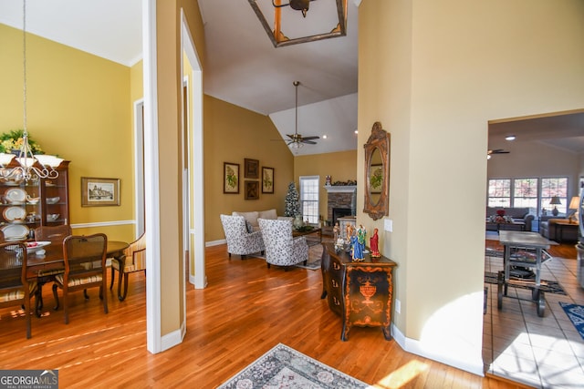 corridor featuring an inviting chandelier, wood-type flooring, and high vaulted ceiling