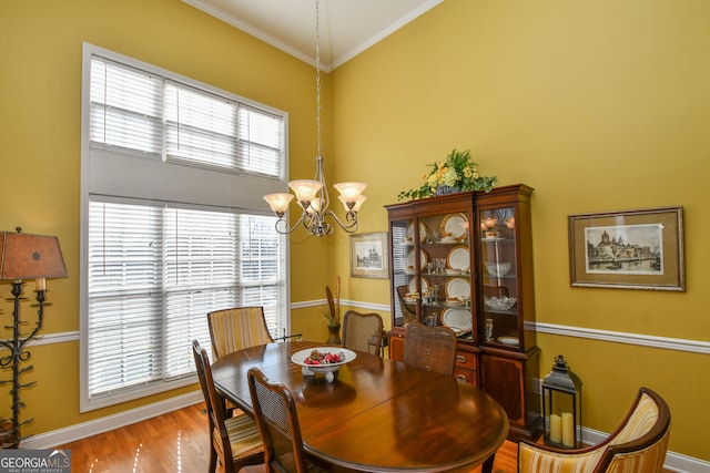 dining area with ornamental molding, wood-type flooring, and an inviting chandelier