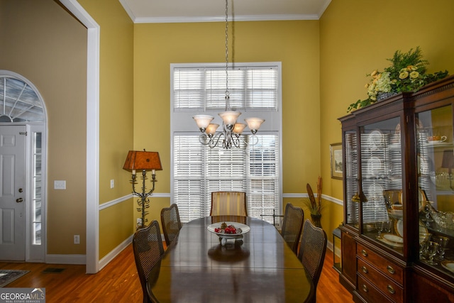 dining room featuring hardwood / wood-style flooring, ornamental molding, and a chandelier