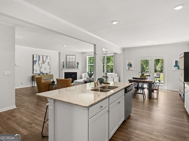 kitchen with white cabinetry, sink, a kitchen island with sink, stainless steel dishwasher, and light stone counters