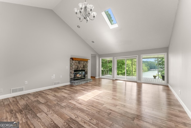 3366 Small Woods Ln, Gainesville, GA 30506 - unfurnished living room featuring a skylight, wood finished floors, high vaulted ceiling, a stone fireplace, and a chandelier