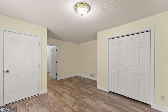 3366 Small Woods Ln, Gainesville, GA 30506 - unfurnished bedroom with a closet, wood finished floors, a textured ceiling, visible vents, and baseboards