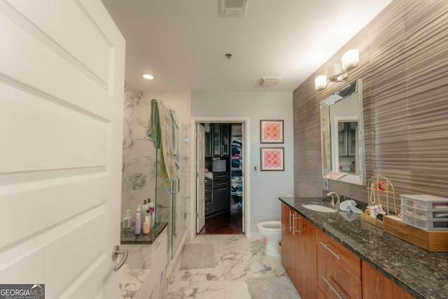 bathroom featuring a shower with door, vanity, and toilet