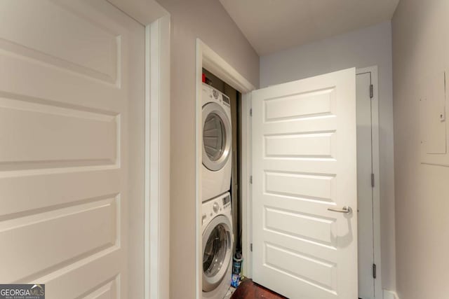 washroom featuring stacked washer and dryer and dark wood-type flooring