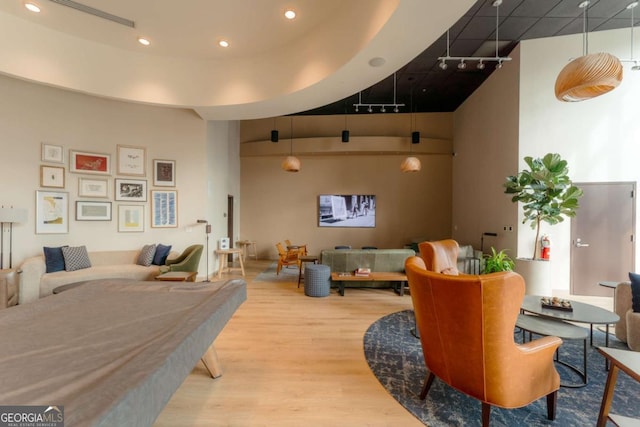 interior space with light wood-type flooring, track lighting, and a high ceiling