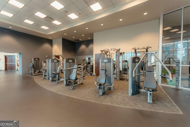 exercise room with a drop ceiling and a towering ceiling