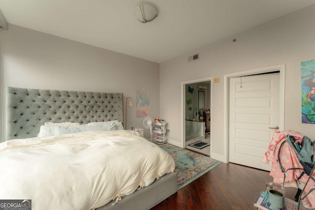 bedroom with ensuite bathroom, dark wood-type flooring, and a closet