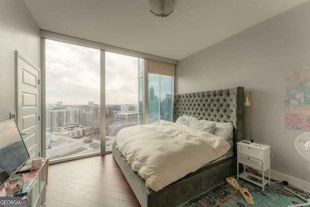 bedroom with hardwood / wood-style flooring, a wall of windows, and access to outside