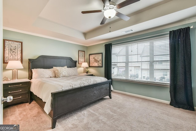 carpeted bedroom featuring ornamental molding, ceiling fan, and a tray ceiling