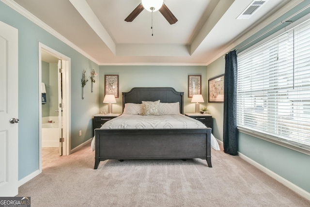 carpeted bedroom featuring multiple windows, ensuite bath, a raised ceiling, and ceiling fan