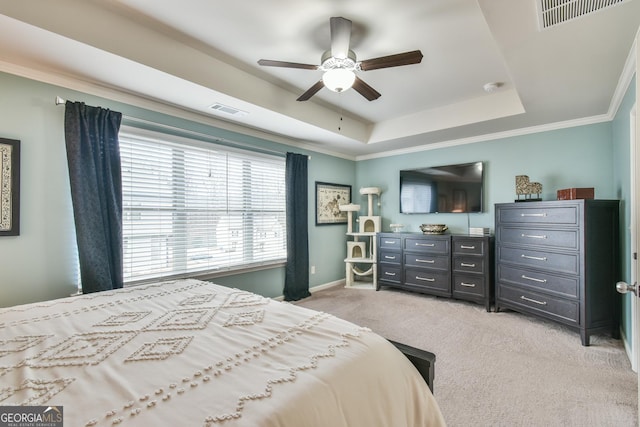 bedroom with ornamental molding, light colored carpet, ceiling fan, and a tray ceiling