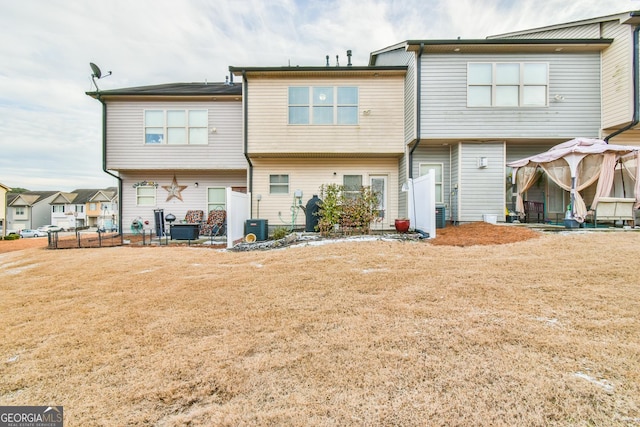 rear view of property featuring central AC and a lawn