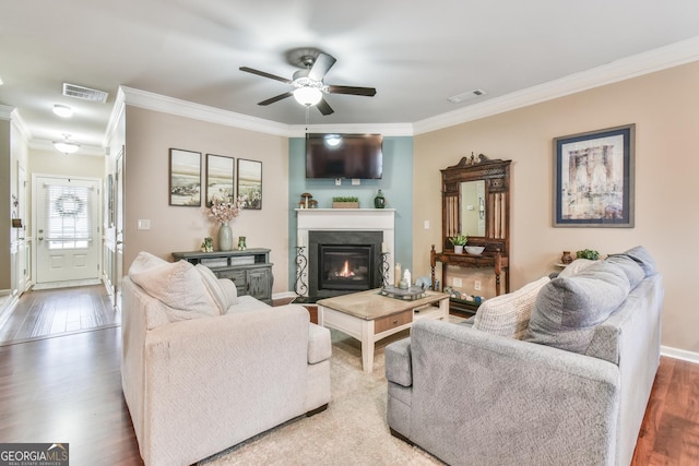 living room with crown molding, wood-type flooring, and ceiling fan