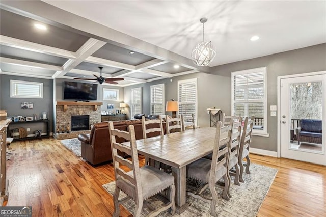 dining space with plenty of natural light, coffered ceiling, a fireplace, beamed ceiling, and light wood-type flooring