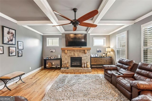 living room featuring ornamental molding, a stone fireplace, and light hardwood / wood-style floors