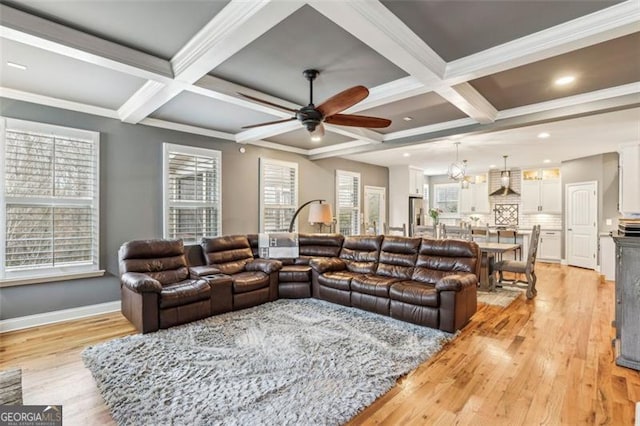 living room featuring coffered ceiling, crown molding, ceiling fan, beam ceiling, and light hardwood / wood-style floors