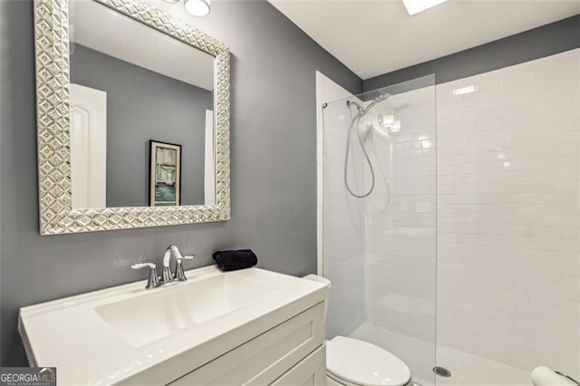 bathroom with vanity, toilet, and tiled shower